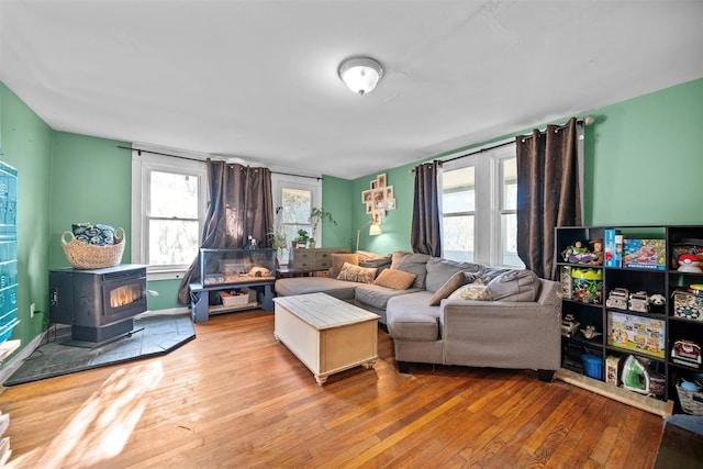 living room with a healthy amount of sunlight, a wood stove, and light hardwood / wood-style flooring