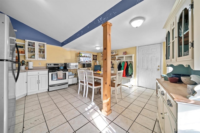 kitchen featuring range with electric stovetop, refrigerator, light tile patterned floors, and vaulted ceiling