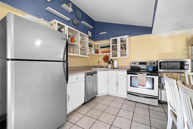 kitchen featuring appliances with stainless steel finishes, vaulted ceiling, sink, white cabinets, and light tile patterned flooring