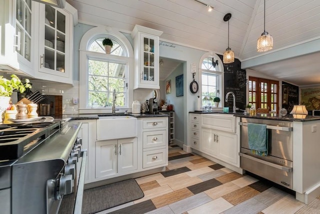 kitchen with pendant lighting, white cabinetry, a wealth of natural light, and vaulted ceiling