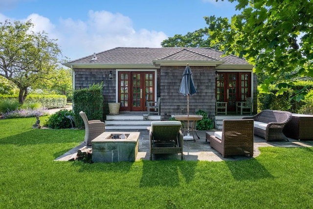 rear view of house with a lawn, a patio area, french doors, and an outdoor living space with a fire pit