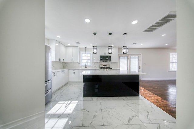 kitchen featuring white cabinetry, stainless steel appliances, backsplash, pendant lighting, and a kitchen island