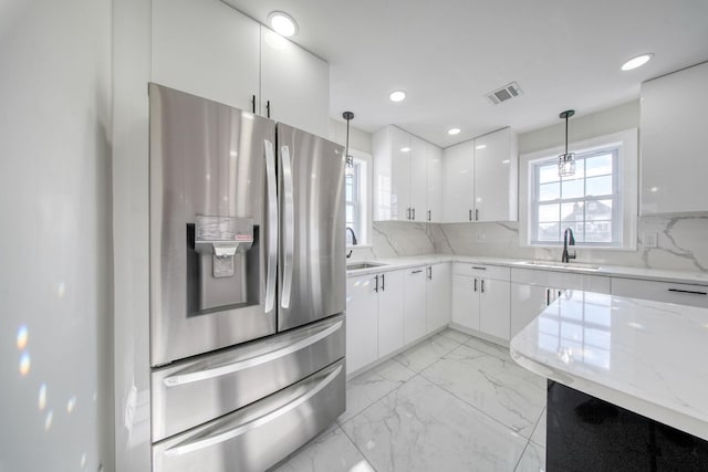 kitchen with backsplash, white cabinets, hanging light fixtures, and stainless steel refrigerator with ice dispenser