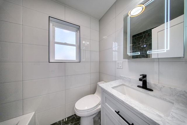 bathroom featuring vanity, toilet, and tile walls