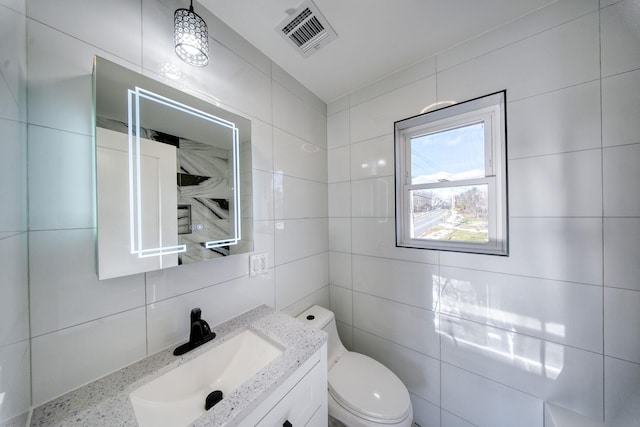 bathroom with decorative backsplash, toilet, tile walls, and vanity