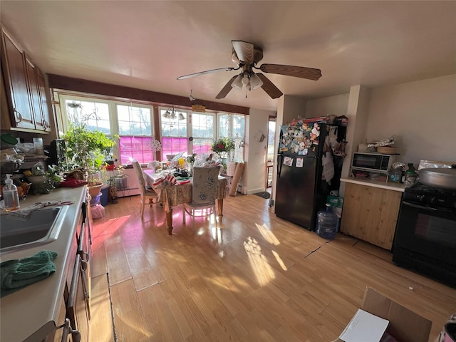 kitchen featuring sink, light hardwood / wood-style flooring, ceiling fan, and black appliances