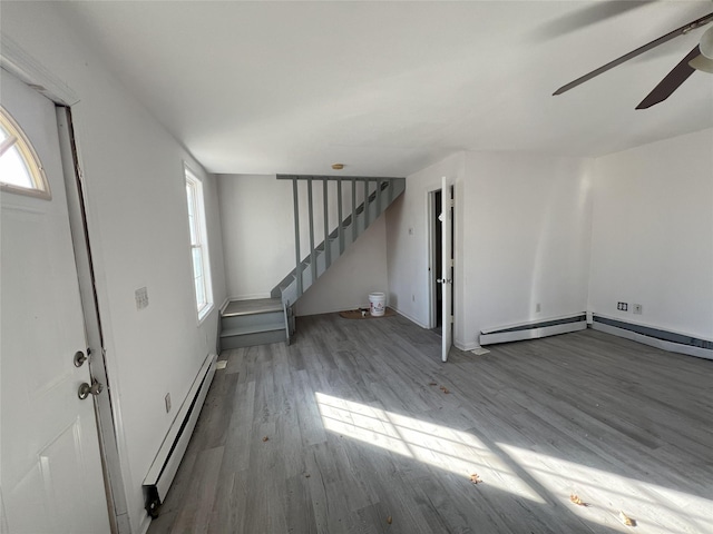 basement featuring hardwood / wood-style floors, ceiling fan, and a baseboard heating unit