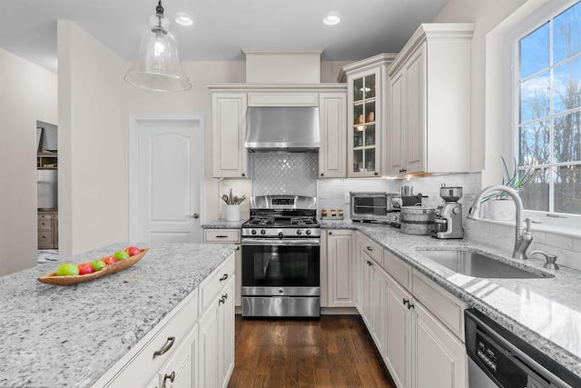 kitchen with pendant lighting, exhaust hood, sink, appliances with stainless steel finishes, and white cabinetry