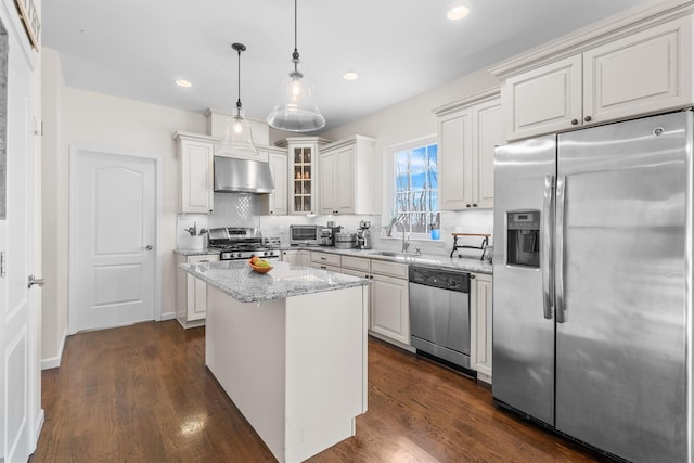 kitchen featuring pendant lighting, sink, range hood, appliances with stainless steel finishes, and a kitchen island