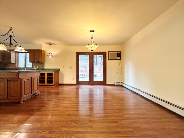 interior space featuring french doors, dark wood-type flooring, a baseboard heating unit, backsplash, and pendant lighting