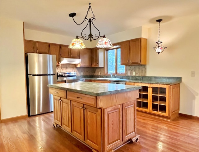 kitchen featuring light wood-type flooring, appliances with stainless steel finishes, a center island, and hanging light fixtures