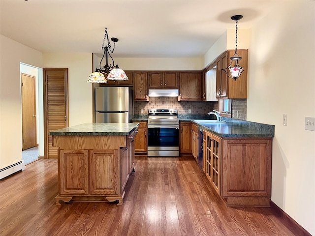 kitchen featuring appliances with stainless steel finishes, dark hardwood / wood-style flooring, sink, decorative light fixtures, and a center island