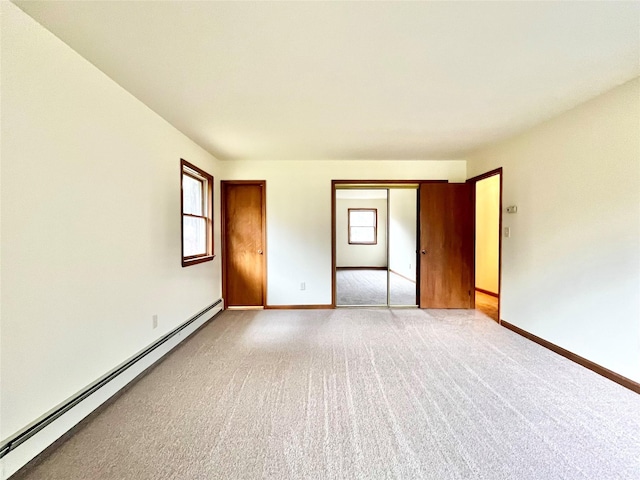 unfurnished bedroom with light carpet, a closet, and a baseboard heating unit