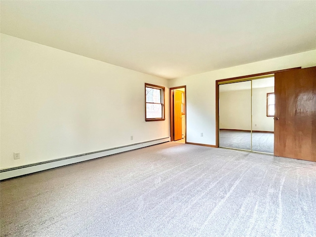 unfurnished bedroom featuring carpet, a closet, and a baseboard heating unit