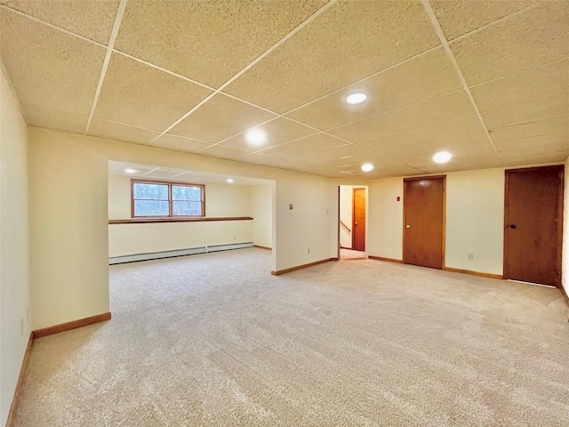 basement with carpet, a baseboard radiator, and a drop ceiling