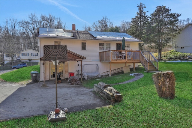 back of property with a patio area, a yard, a deck, and solar panels