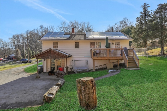 back of house featuring a wooden deck, a yard, and solar panels