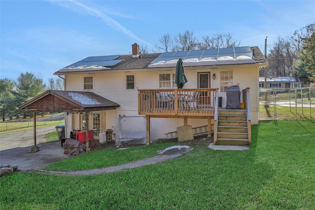 rear view of property with a lawn, solar panels, and a wooden deck