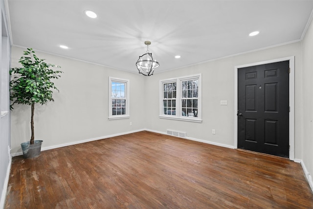 foyer entrance featuring visible vents, baseboards, an inviting chandelier, crown molding, and wood finished floors
