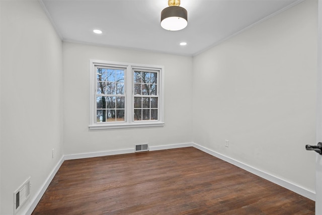 spare room with ornamental molding, visible vents, baseboards, and dark wood-style flooring