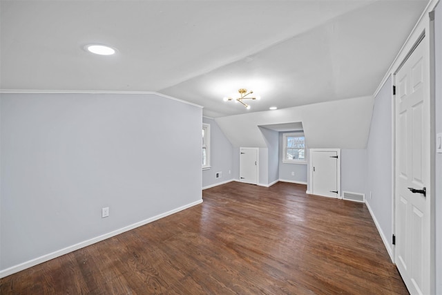 additional living space featuring dark wood-style flooring, baseboards, lofted ceiling, and visible vents