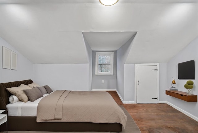 bedroom featuring wood finished floors, baseboards, and vaulted ceiling