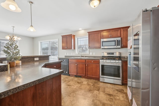 kitchen featuring stainless steel appliances, decorative light fixtures, a chandelier, and sink