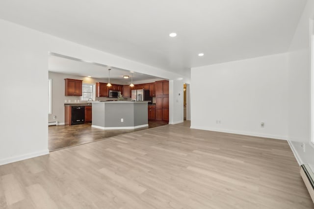 unfurnished living room with a baseboard radiator, sink, and light hardwood / wood-style flooring