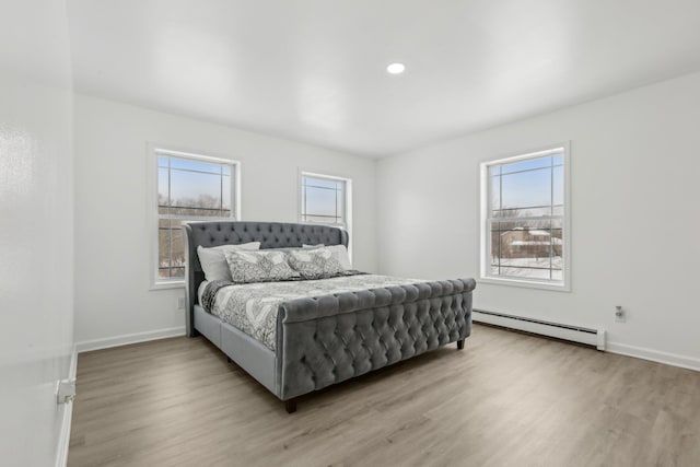 bedroom with a baseboard radiator and light wood-type flooring