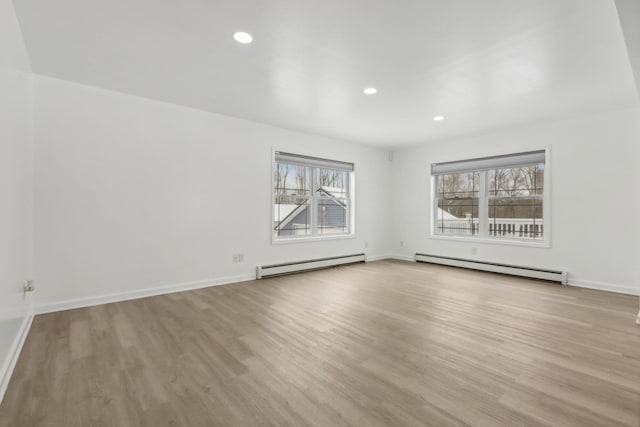 unfurnished room with a baseboard heating unit and light hardwood / wood-style flooring