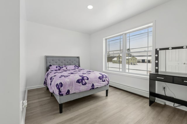 bedroom with a baseboard radiator and wood-type flooring