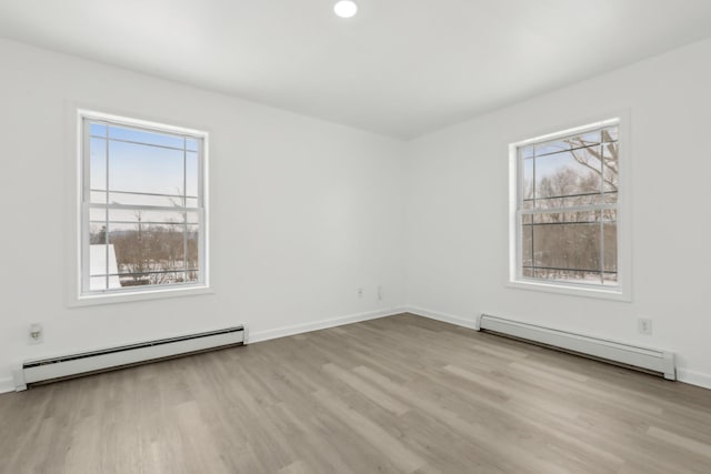 unfurnished room with baseboard heating and light hardwood / wood-style floors