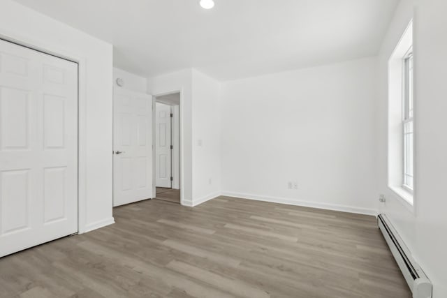 unfurnished bedroom featuring a baseboard radiator and light hardwood / wood-style floors