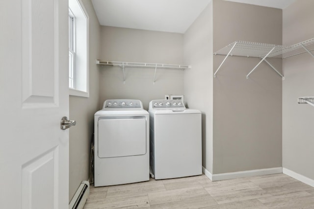 clothes washing area with washer and clothes dryer, a baseboard radiator, and light wood-type flooring