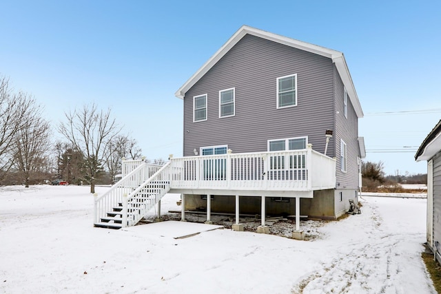 snow covered rear of property with a wooden deck