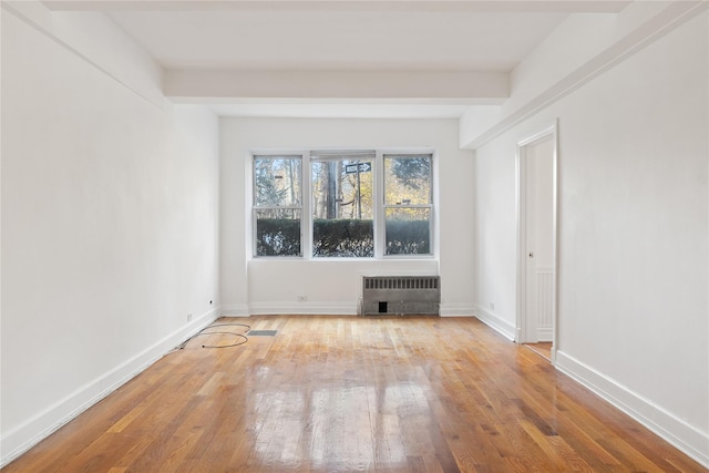 unfurnished living room with beam ceiling, light wood-type flooring, and radiator