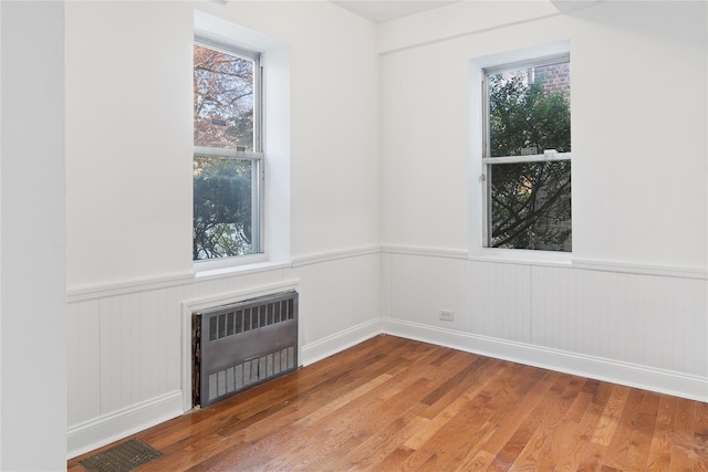 empty room featuring radiator heating unit and hardwood / wood-style floors