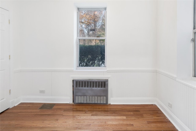 interior details with wood-type flooring and radiator heating unit