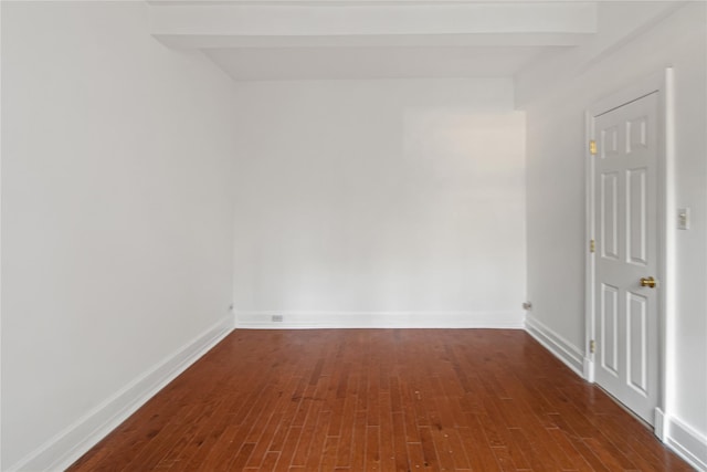 empty room with beamed ceiling and dark hardwood / wood-style flooring