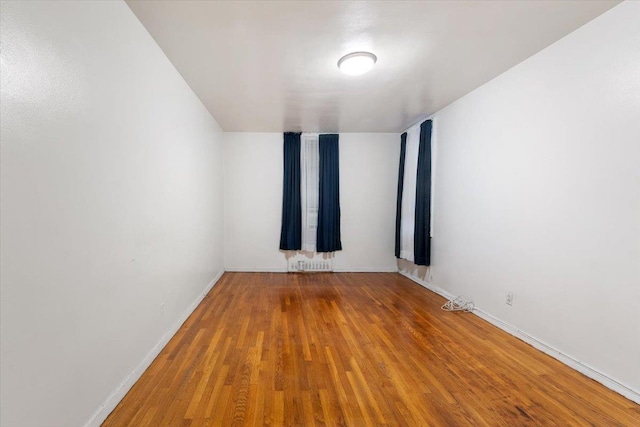 unfurnished room featuring radiator heating unit and hardwood / wood-style flooring