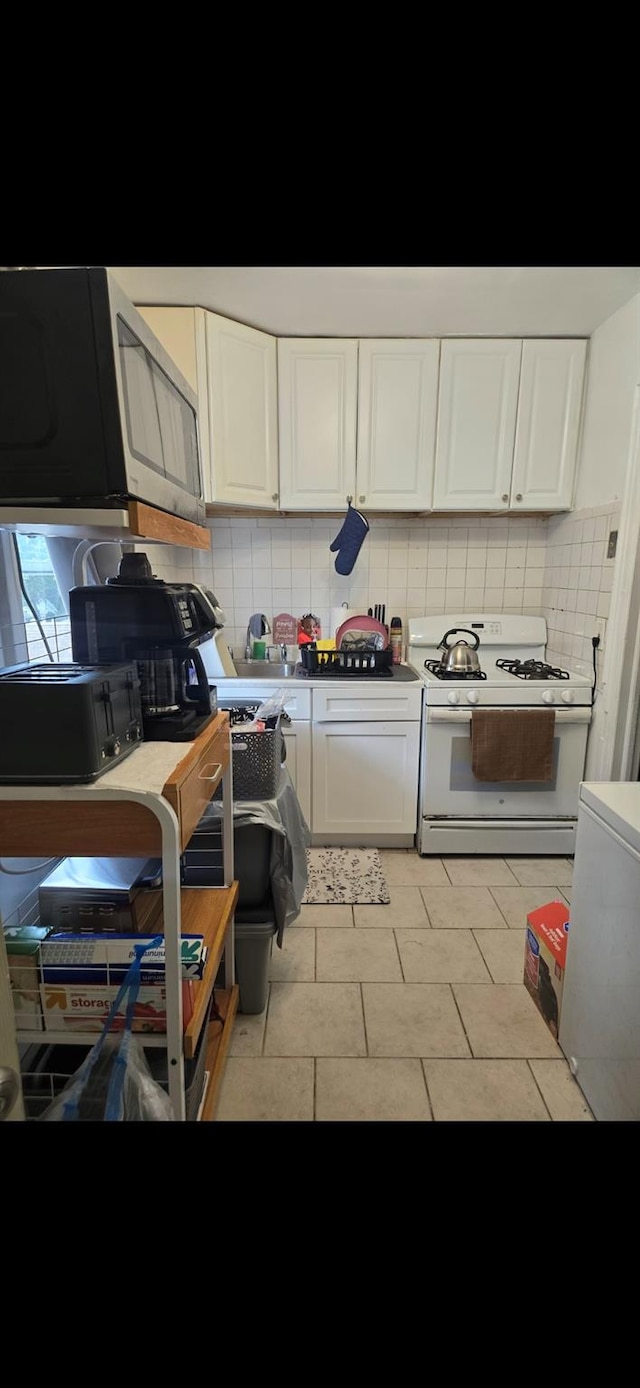 kitchen with decorative backsplash, white gas range oven, and white cabinetry