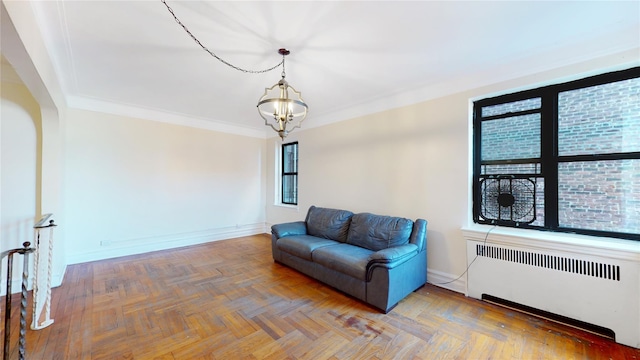 sitting room featuring a notable chandelier, radiator heating unit, ornamental molding, and parquet flooring