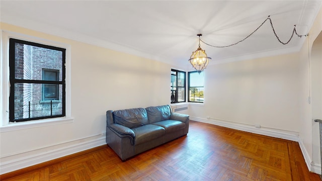 living area featuring parquet flooring, ornamental molding, and a notable chandelier