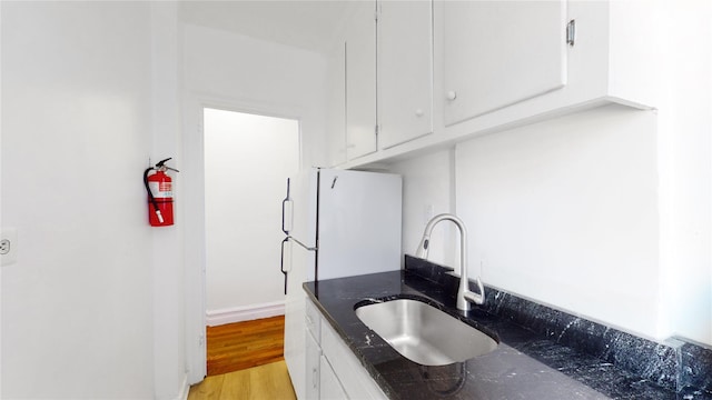 kitchen with white cabinets, white refrigerator, light wood-type flooring, and sink