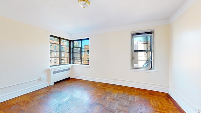 spare room featuring radiator heating unit and dark parquet floors