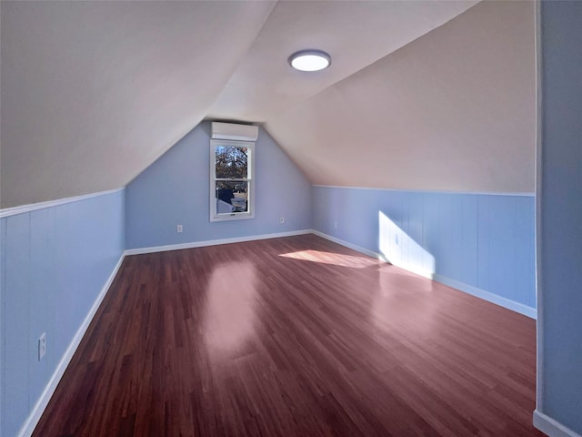 additional living space with a wall mounted AC, dark hardwood / wood-style flooring, and lofted ceiling