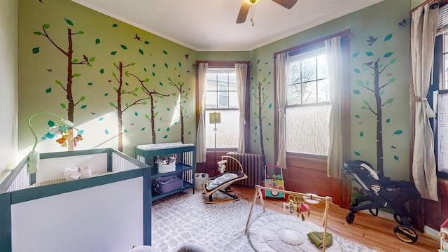 interior space with hardwood / wood-style floors, ceiling fan, ornamental molding, and radiator