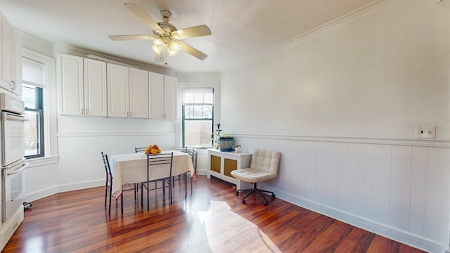 dining area with ceiling fan, ornamental molding, and dark wood-type flooring