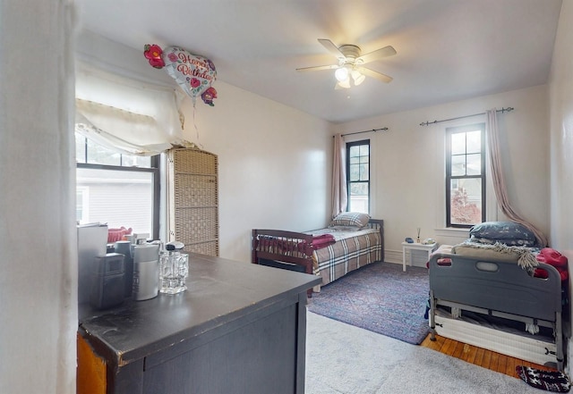 bedroom with hardwood / wood-style floors, ceiling fan, and multiple windows