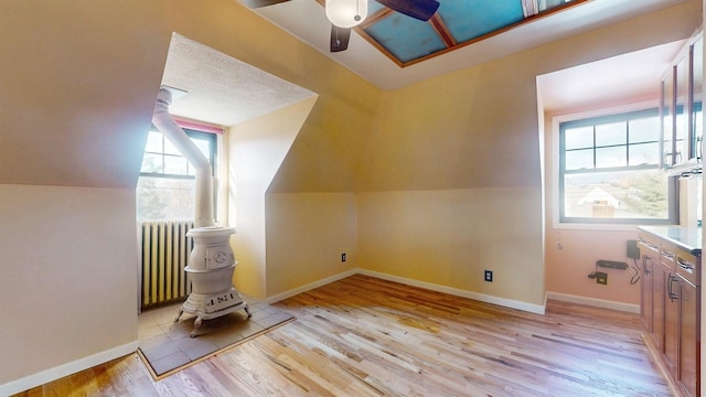 bonus room with light wood-type flooring, vaulted ceiling, radiator, and a healthy amount of sunlight